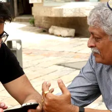 An older man in a yarmulka speaks with younger bearded man.  