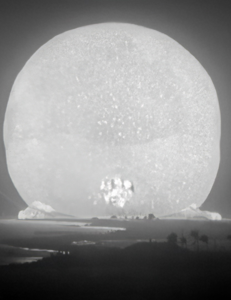 Black and white shot of a large beam of light mushrooming following an atomic bomb