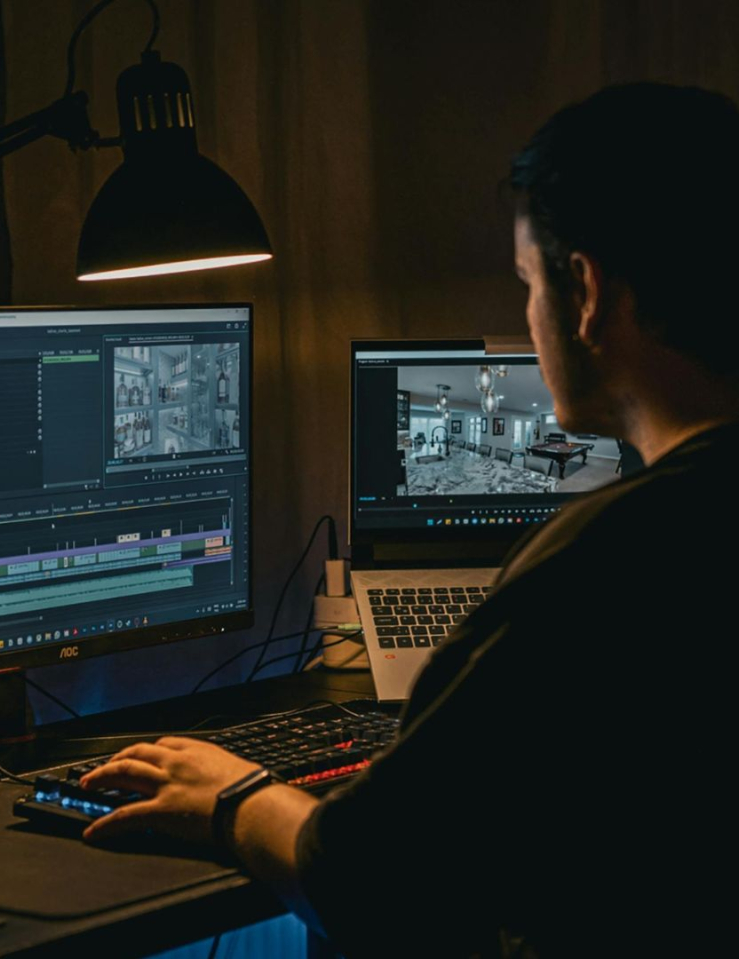 Man sits at his work computer setup where he's seen using video editing software