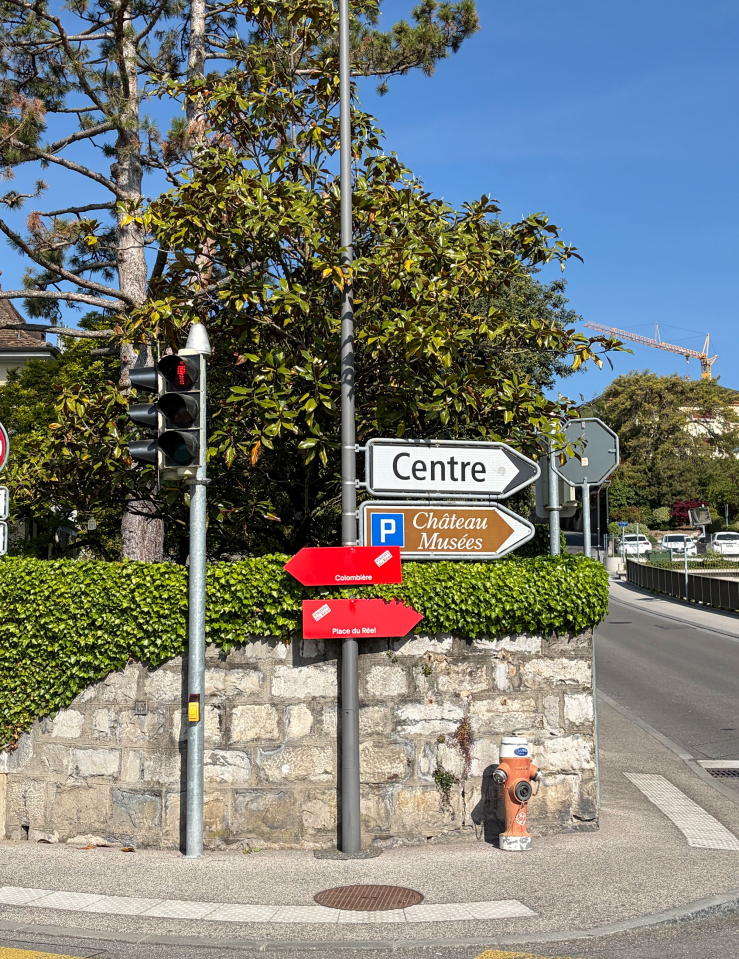 The festival's signature red location signs affixed to a regular road sign.