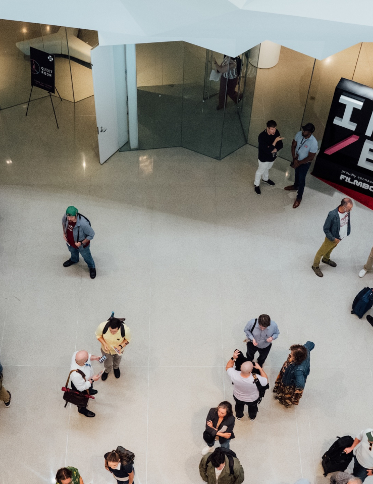 Bird's eye view of a gathering of folks with a step-and-repeat branded as IND/EX seen in the background